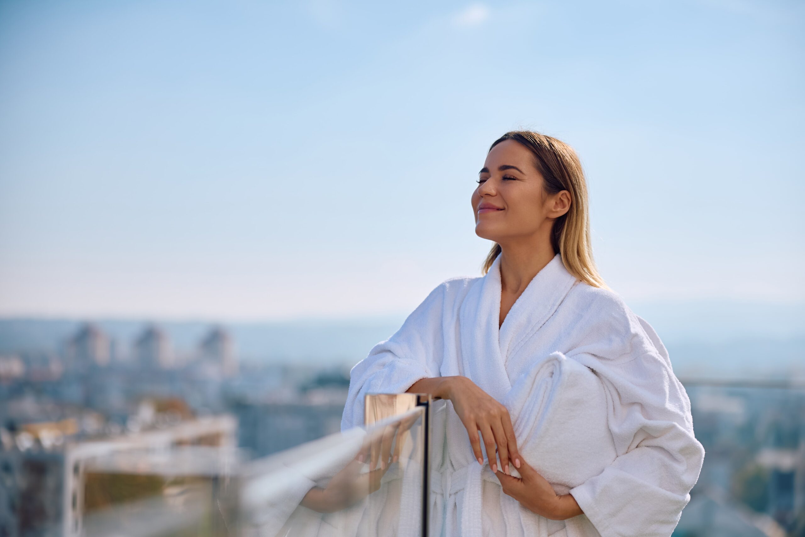 Žena uživa u opuštajućem trenutku na terasi wellness spa centra na poslednjem spratu Sheraton hotela, s panoramskim pogledom na grad.